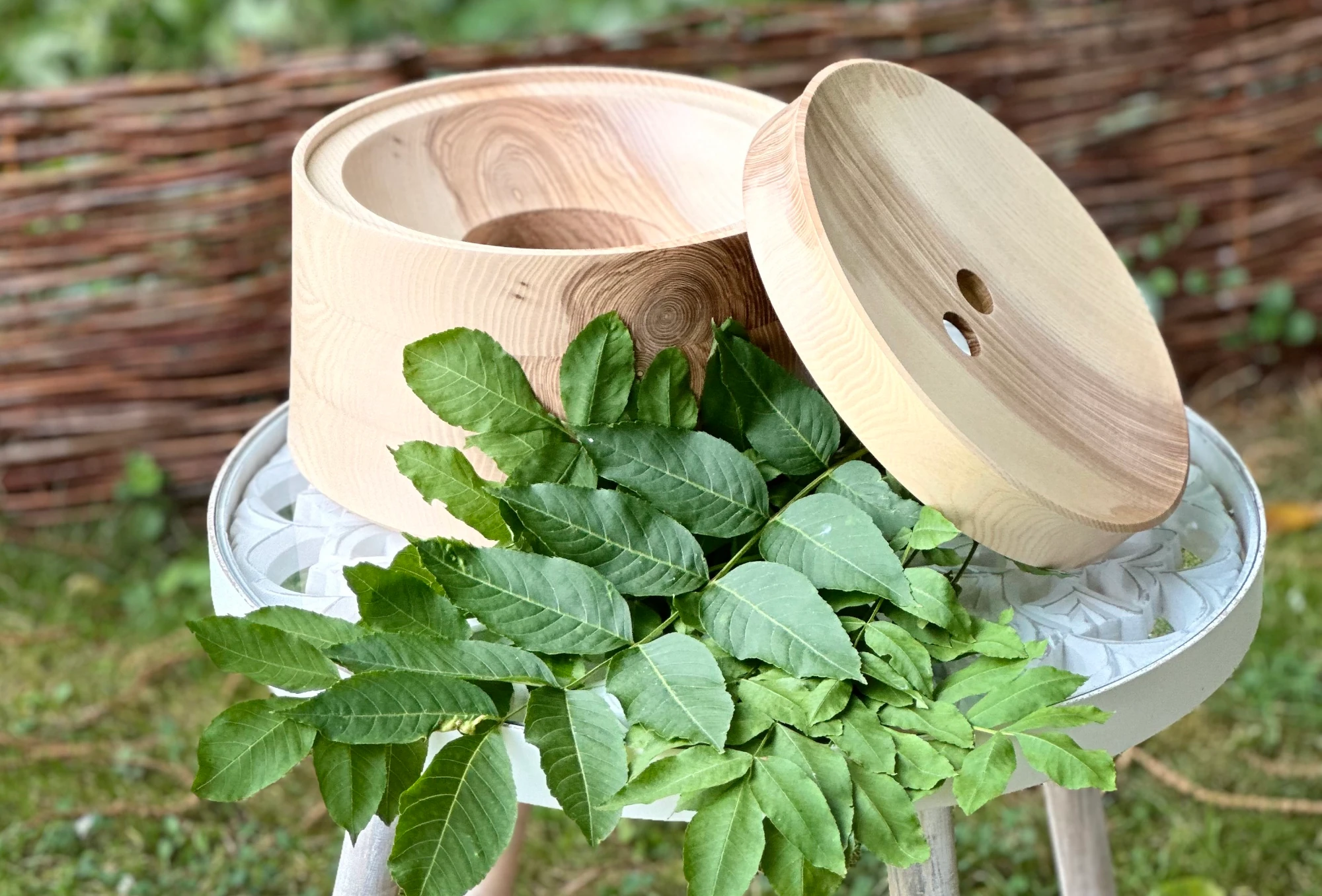 Echtholz Sockel und Deckel aus Esche für AcalaQuell Stand Wasserfilter auf einem Tisch im grünen Garten.