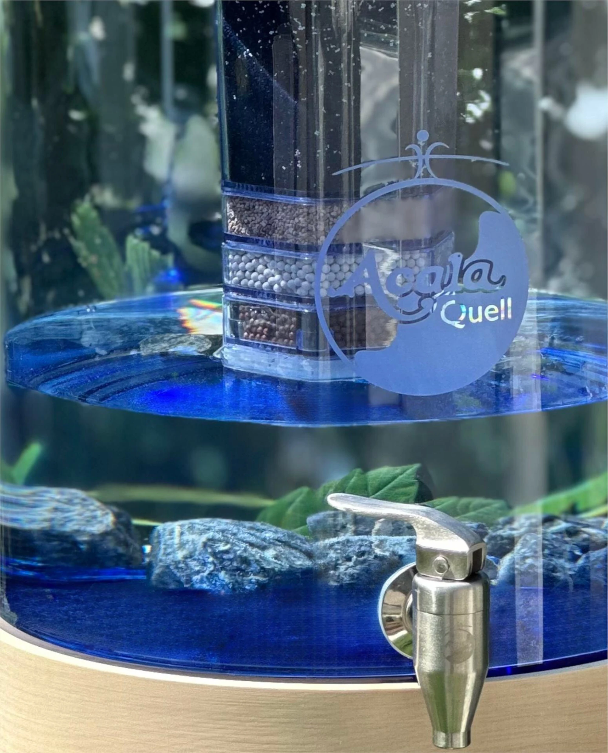 Ausschnitt eines Standwasserfilters von Acala mit blauem Glastank und Sockel aus Ahorn Echtholz.