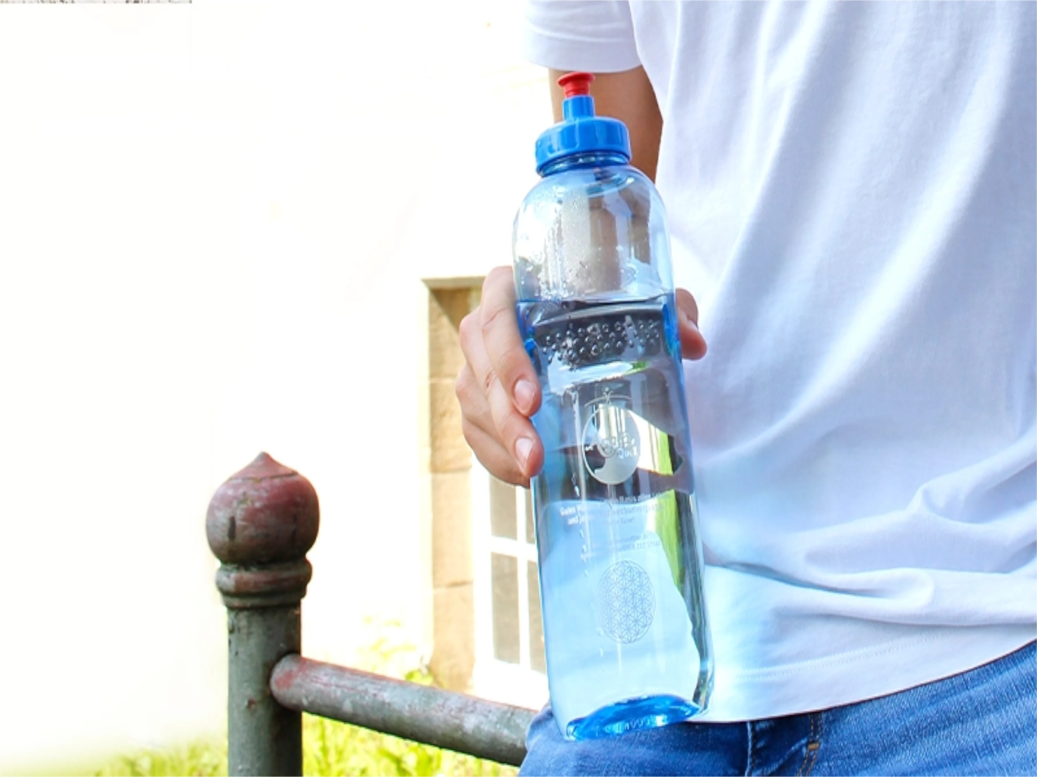 Man sieht eine 1 Liter Tritanflasche von Acala in der Hand von einem Mann, der an einem Metallgeländer lehnt.