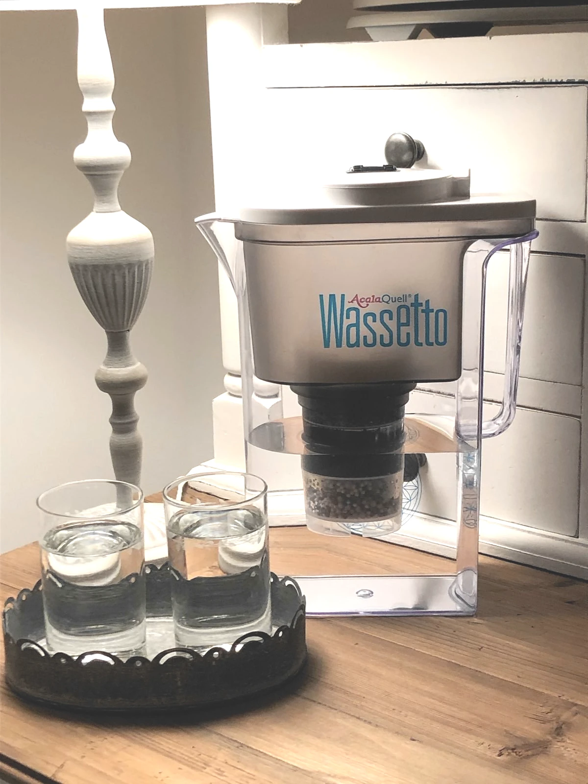 Wassetto steht auf einer holzplatte neben einer Tischlampe und einem Glas mit waser