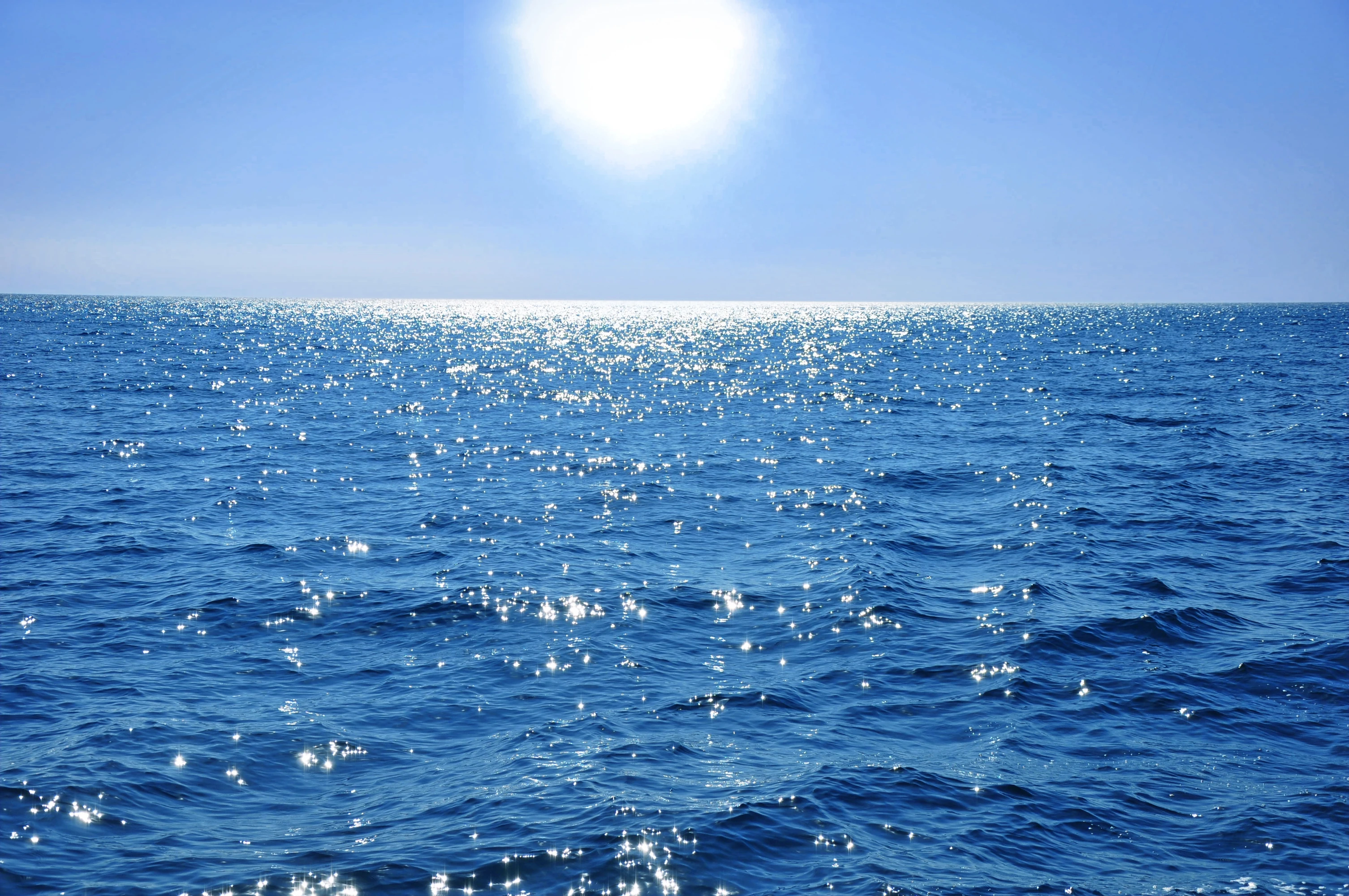 Blaues offenes Meer, blauer Himmel, die Sonne spiegelt sich auf dem Wasser.