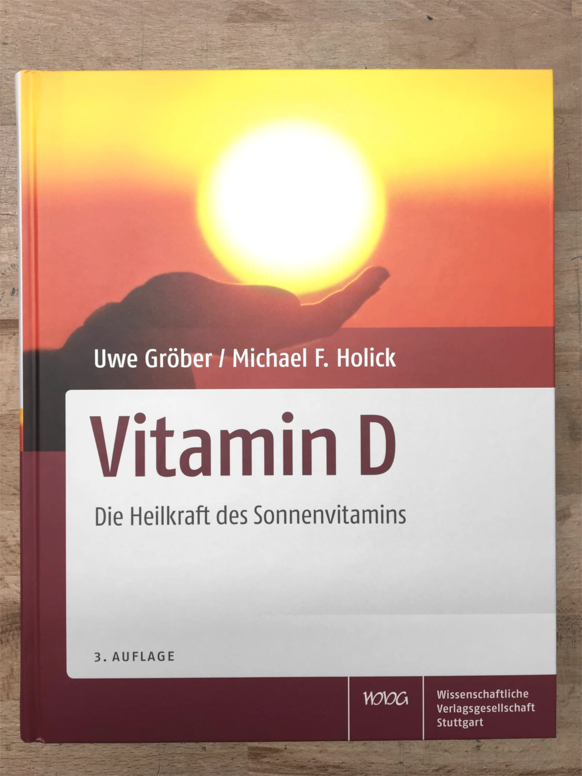 Zu sehen ist die Vorderseite des Buches „Vitamin D“ von Uwe Gröber. Zu sehen ist darauf ein Sonnenuntergang und Hände, die unter der Sonne sind, sodass es aussieht, als würden diese die Sonne halten.