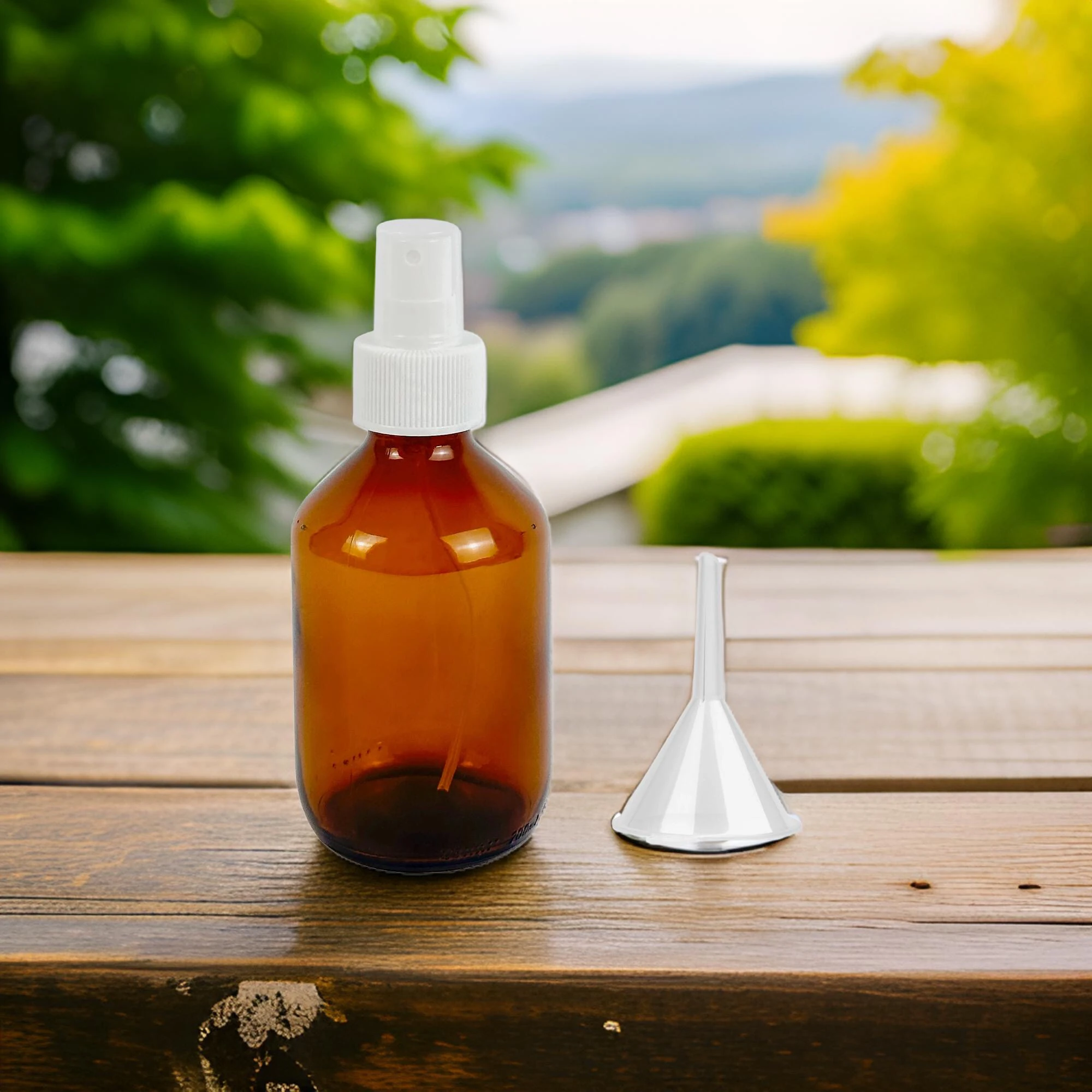 Zu sehen ist die Braunglas Flasche 200ml, der Sprühkopf Mefi S und ein kleiner Einfülltrichter von Acala. Die Flasche steht auf einem braunen Holztisch, im Hintergrund sieht man verschwommen grüne Blätter von Bäumen. 