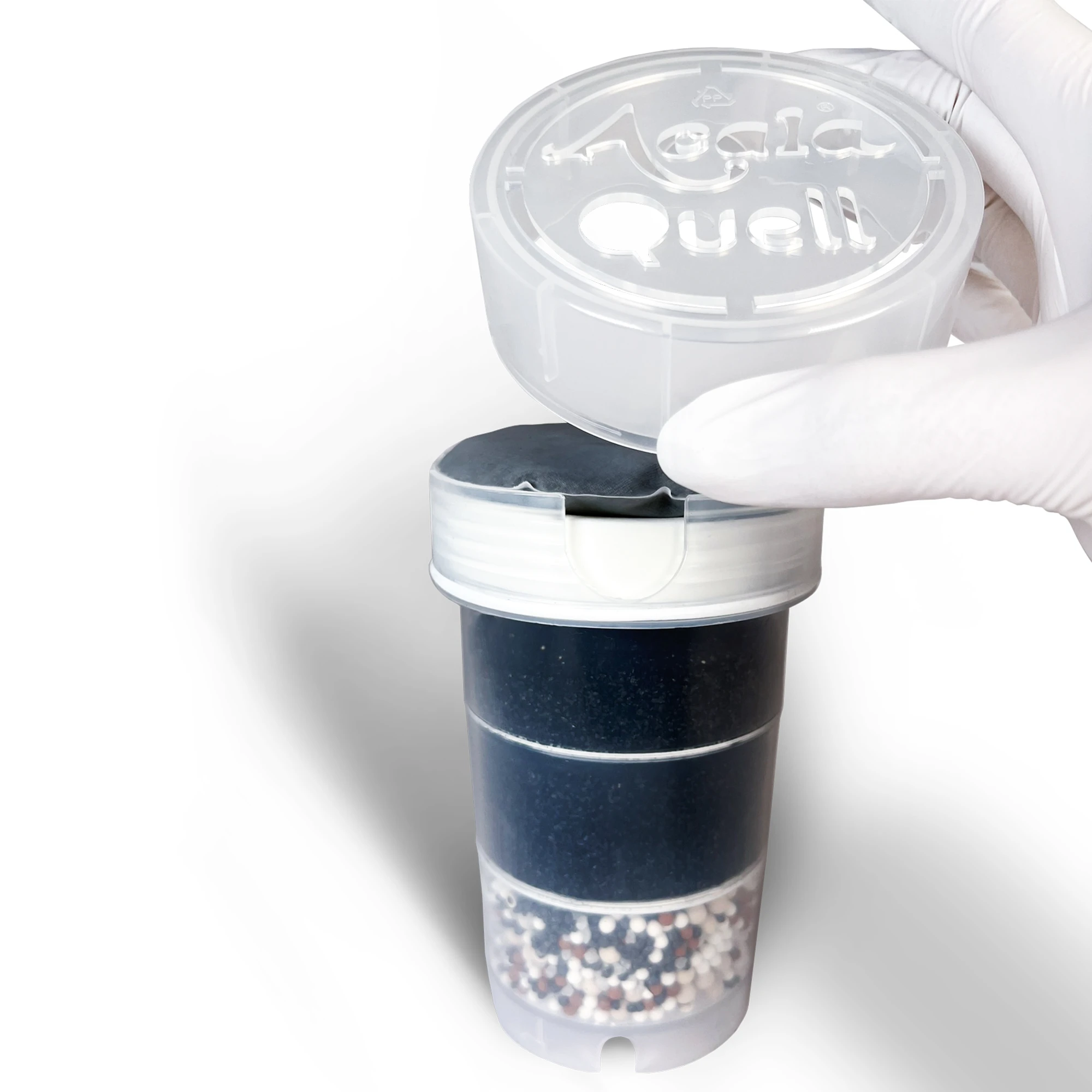 Eine Acala Quell Filterkartusche für Kannenwasserfilter mit einem Mikroschwamm und einem Kalkfilter Pad in der Kartuschenkrone. Eine Hand mit einem weißen Handschuh hält den Kronendeckel hoch in der Hand und klickt ihn auf die Filterkartusche.