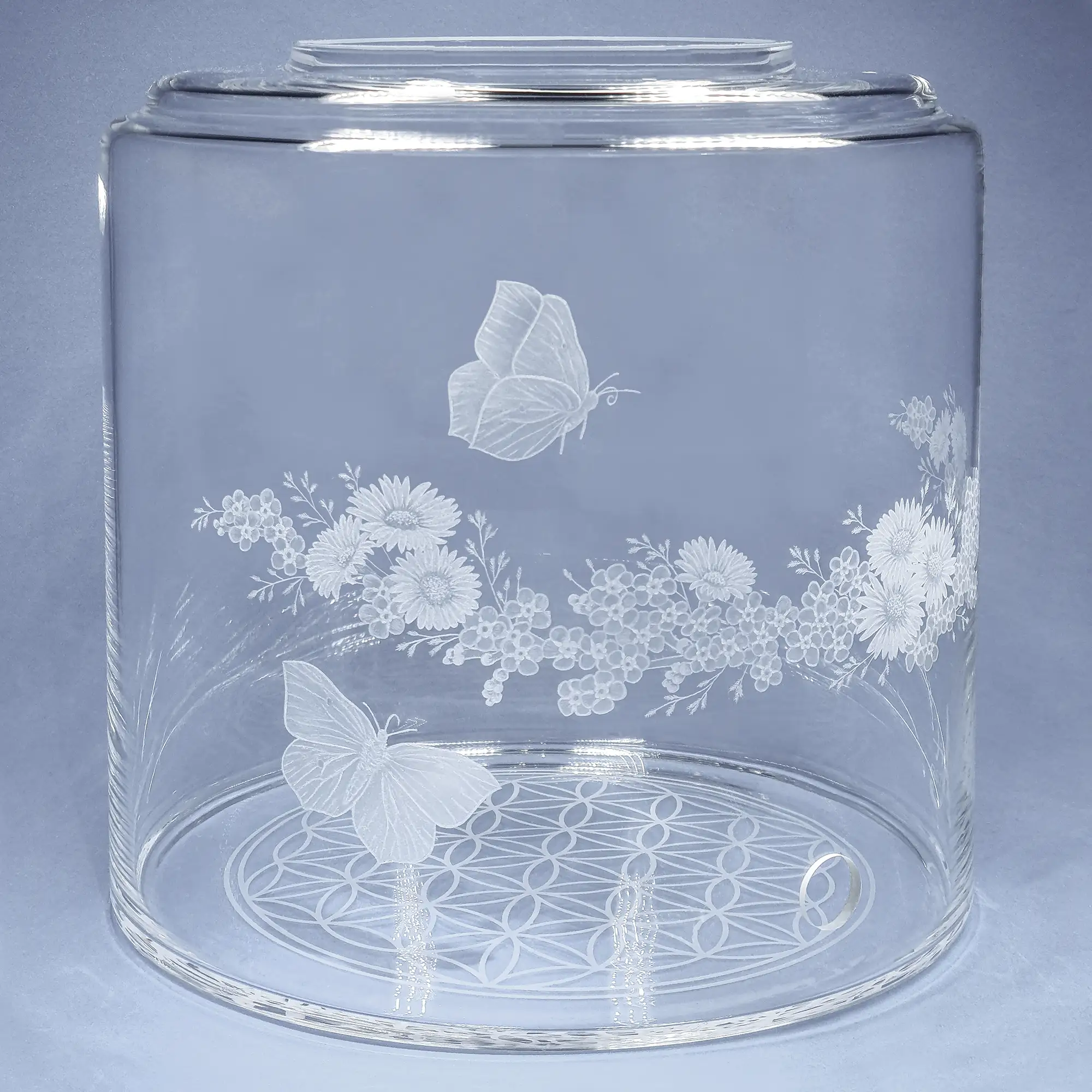 Vorratstank aus Glas für einen 8Liter Acala Wasserfilter in klarem Glas mit dem gravierten Kranz,umlaufende um das runde Glas.In dem Granz sind Vergissmeinnicht, Schmetterlinge und Gänseblümchen.Linke Ansicht.