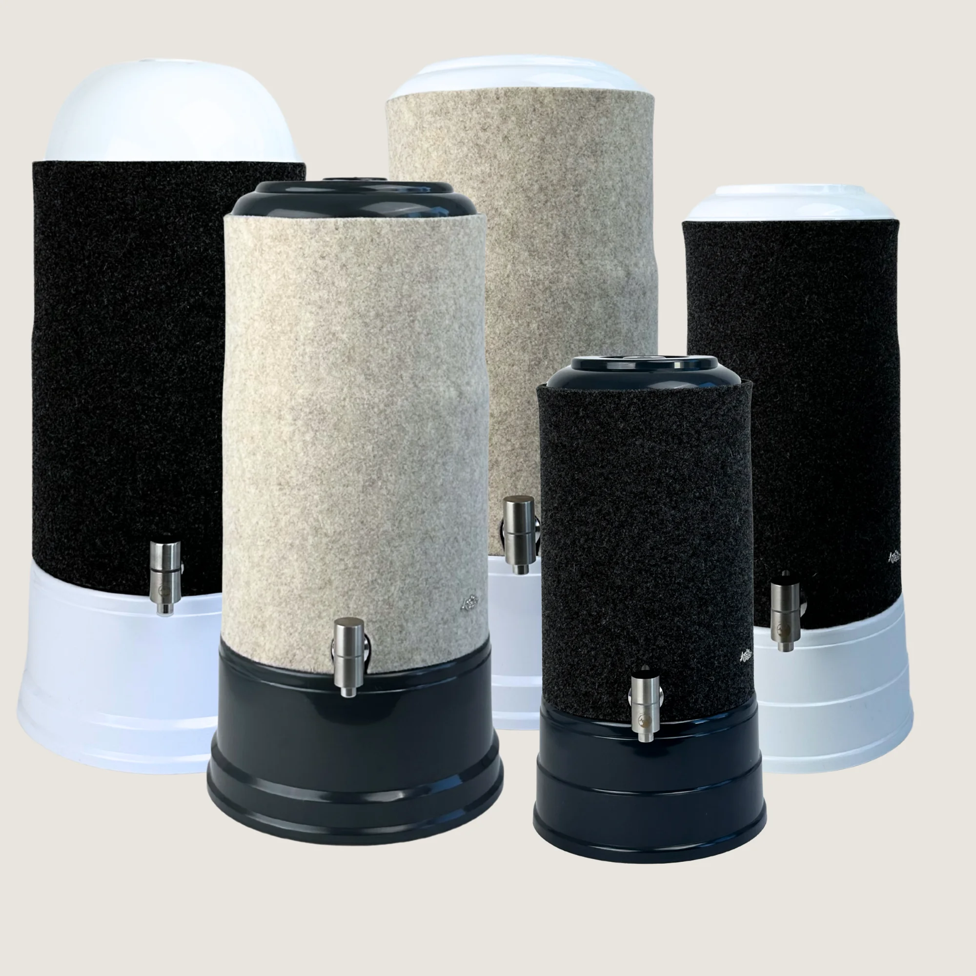 Fünf verschieden große Stand Wasserfilter von Acala mit Schurwolle Lichtschutzüberzügen in anthrazit und beige.
