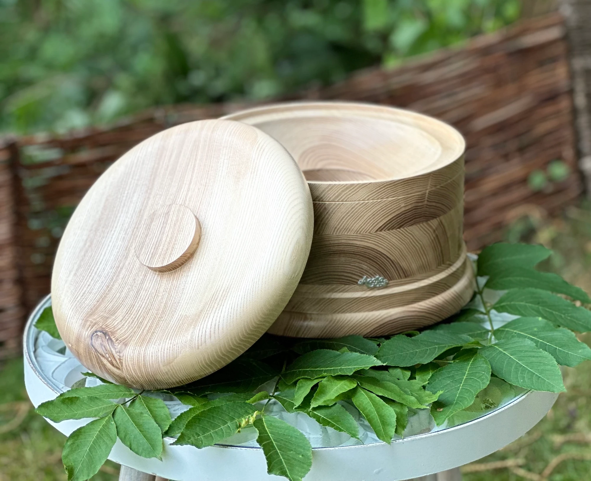 Echtholz Sockel und Deckel aus Esche für AcalaQuell Stand Wasserfilter auf einem Tisch im grünen Garten.