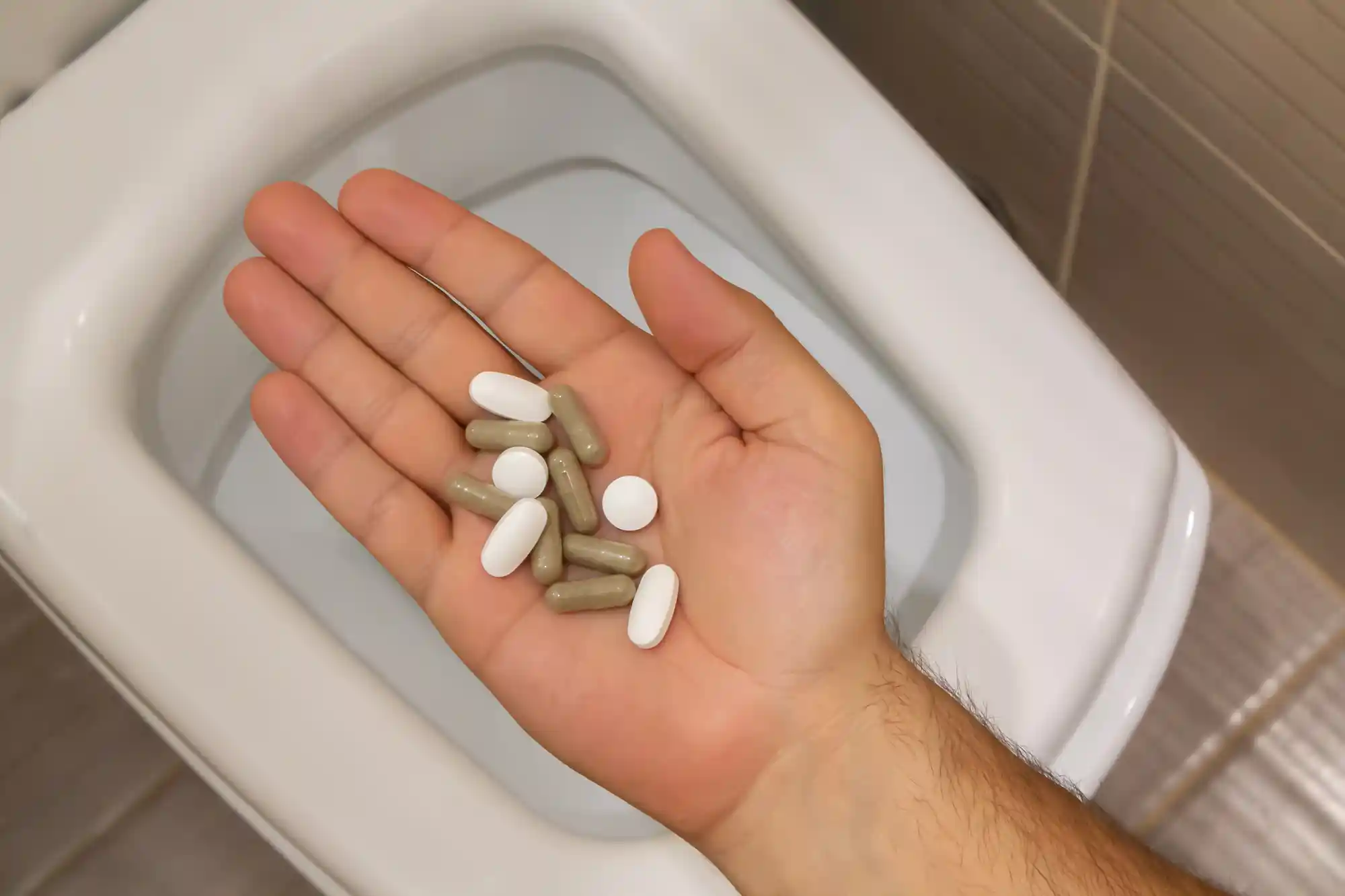 Ein WC, avor eine ahnd mit Pillen
