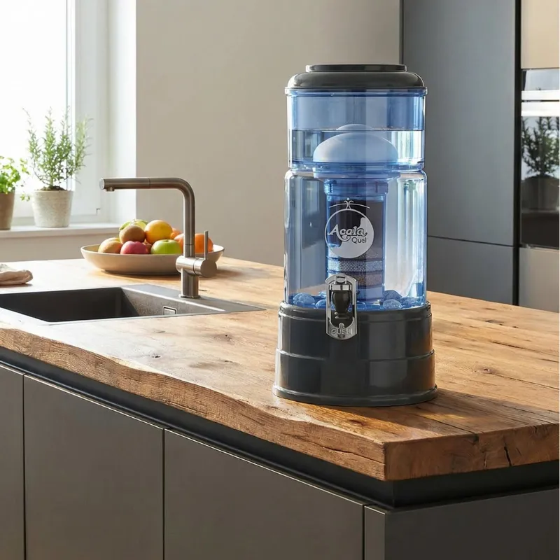 Wasserfilter Mini mit blauem Glas anthrazitfarbenem Deckel und Sockel vollgefüllt mit Wasser steht in der Küche auf einer Insel