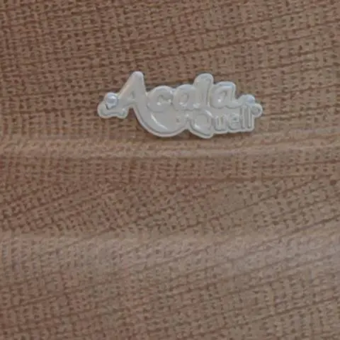 Ausschnitt des silbernen AcalaQuell Logos auf einem Echtholzsockel aus Eiche für die Stand Wasserfilter.