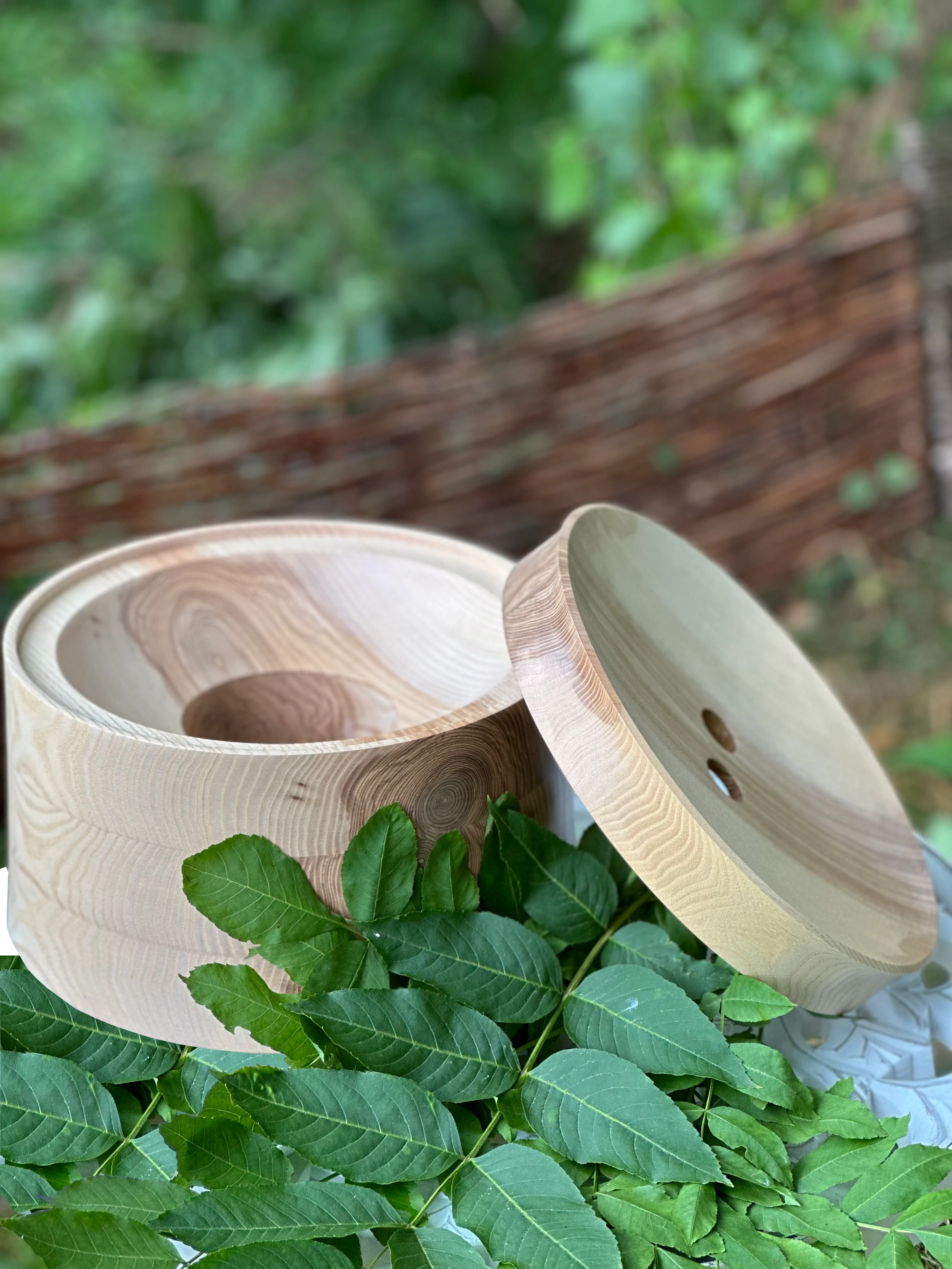 Echtholz Sockel und Deckel aus Esche für AcalaQuell Stand Wasserfilter auf einem Tisch im grünen Garten.