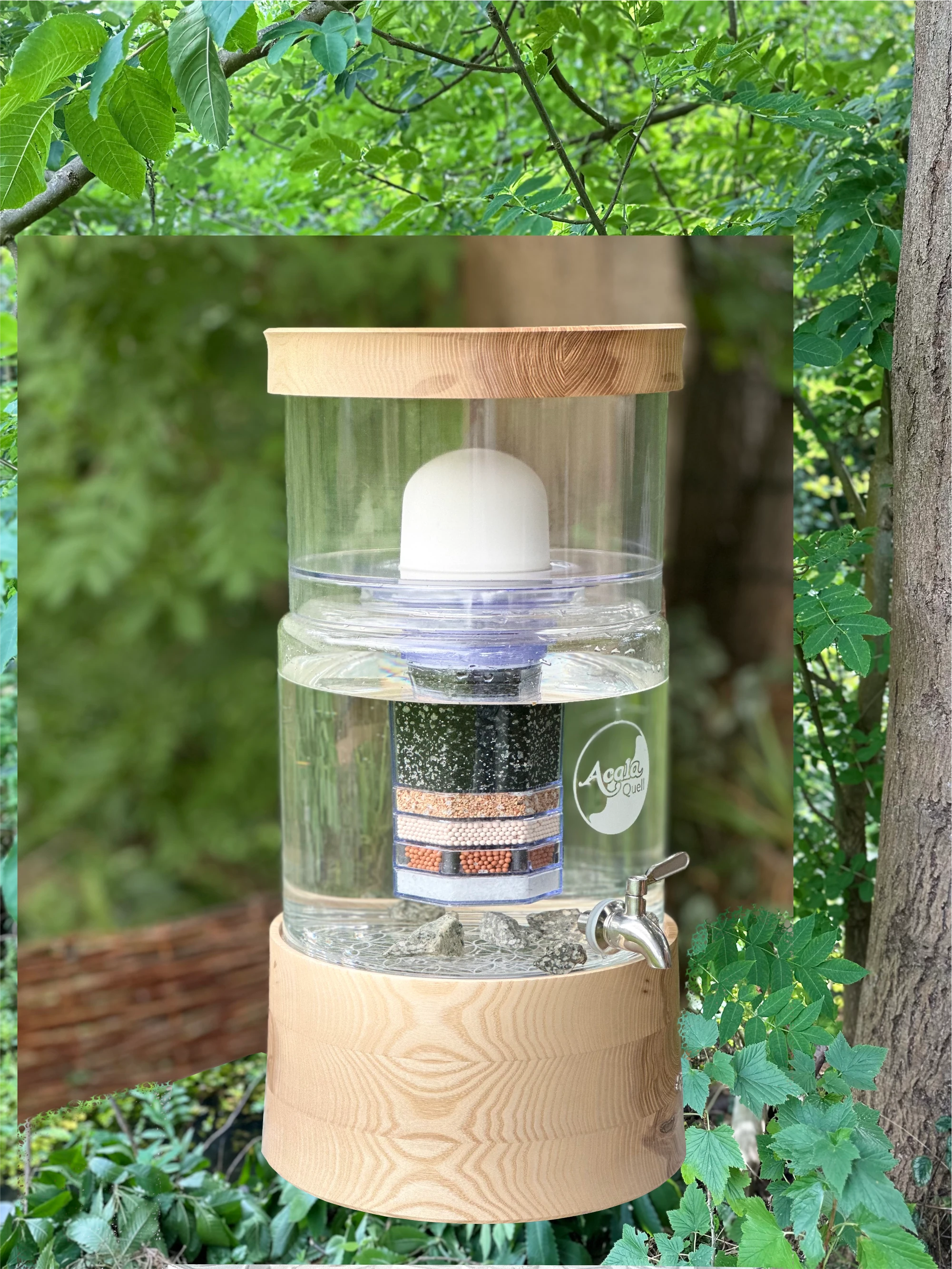 Acala Stand Wasserfilter Smart mit Echtholz Sockel und Deckel aus Esche auf einen kleinen Tisch in einem grünen Garten.
