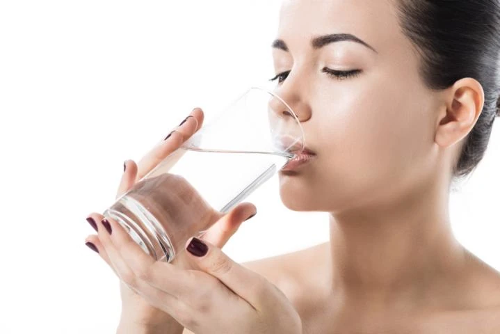 junge Frau trinkt Wasser aus einem Glas.