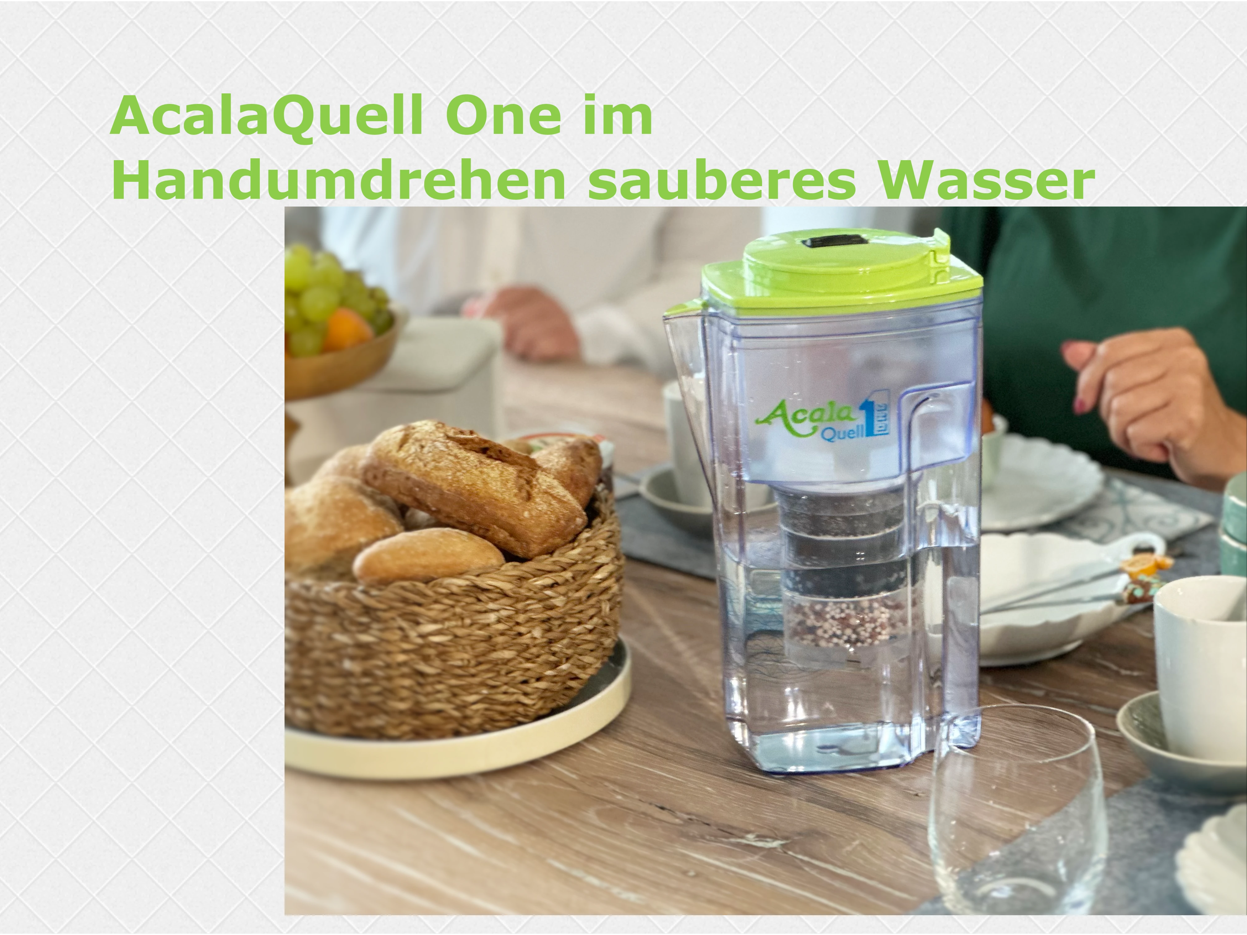 Zu sehen ist der AcalaQuell ONE Kannen Wasserfilter mit Deckel in grün. Er steht auf einem gedeckten Frühstückstisch, im Hintergrund sieht man Personen.