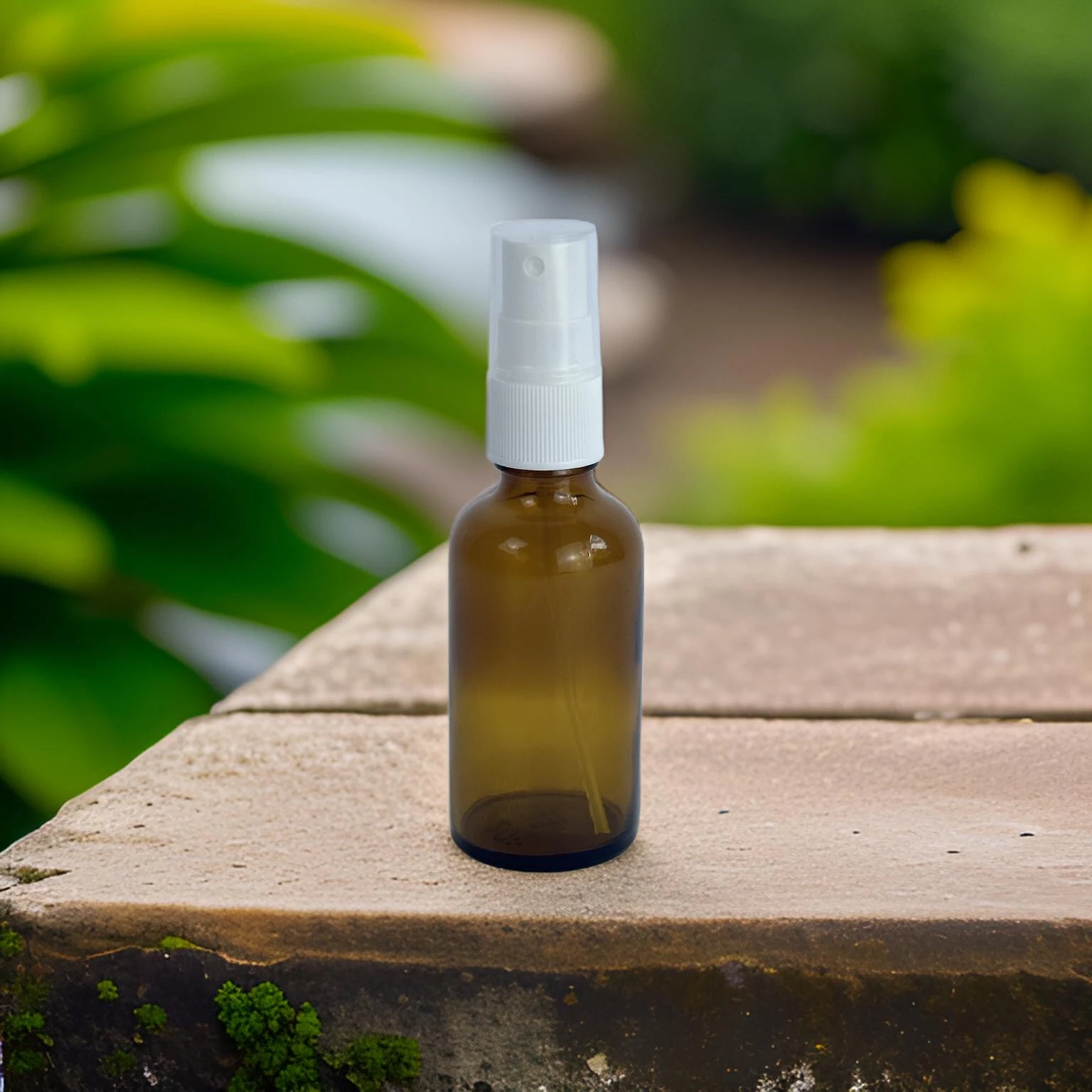 Zu sehen ist die Braunglas Flasche 50ml und der Sprühkopf Mefi S von Acala. Die Flasche steht auf einem braunen Holztisch, im Hintergrund sieht man verschwommen grüne Pflanzen. 