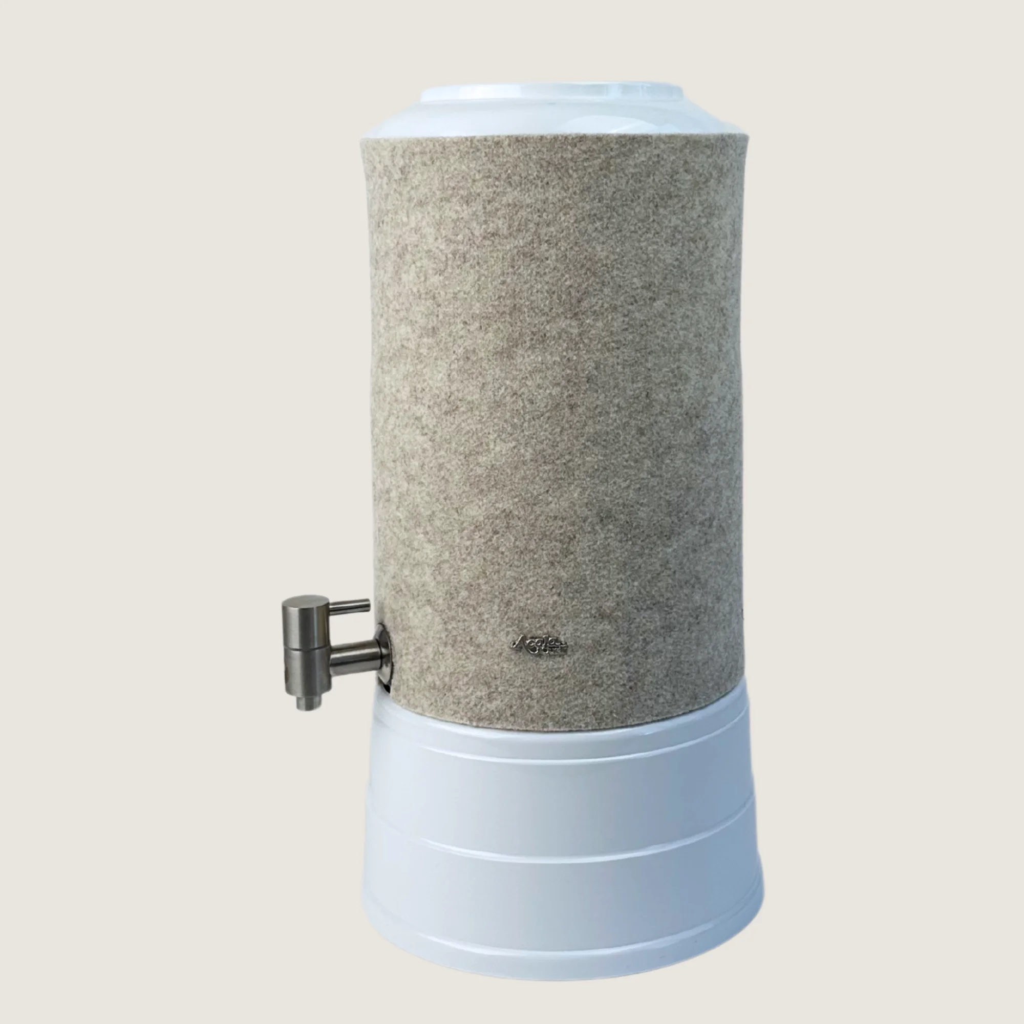 AcalaQuell Mini mit Sockel und Deckel in weiß, Edelstahl Wasserhahn und Schurwolle Lichtschutzüberzug in beige.