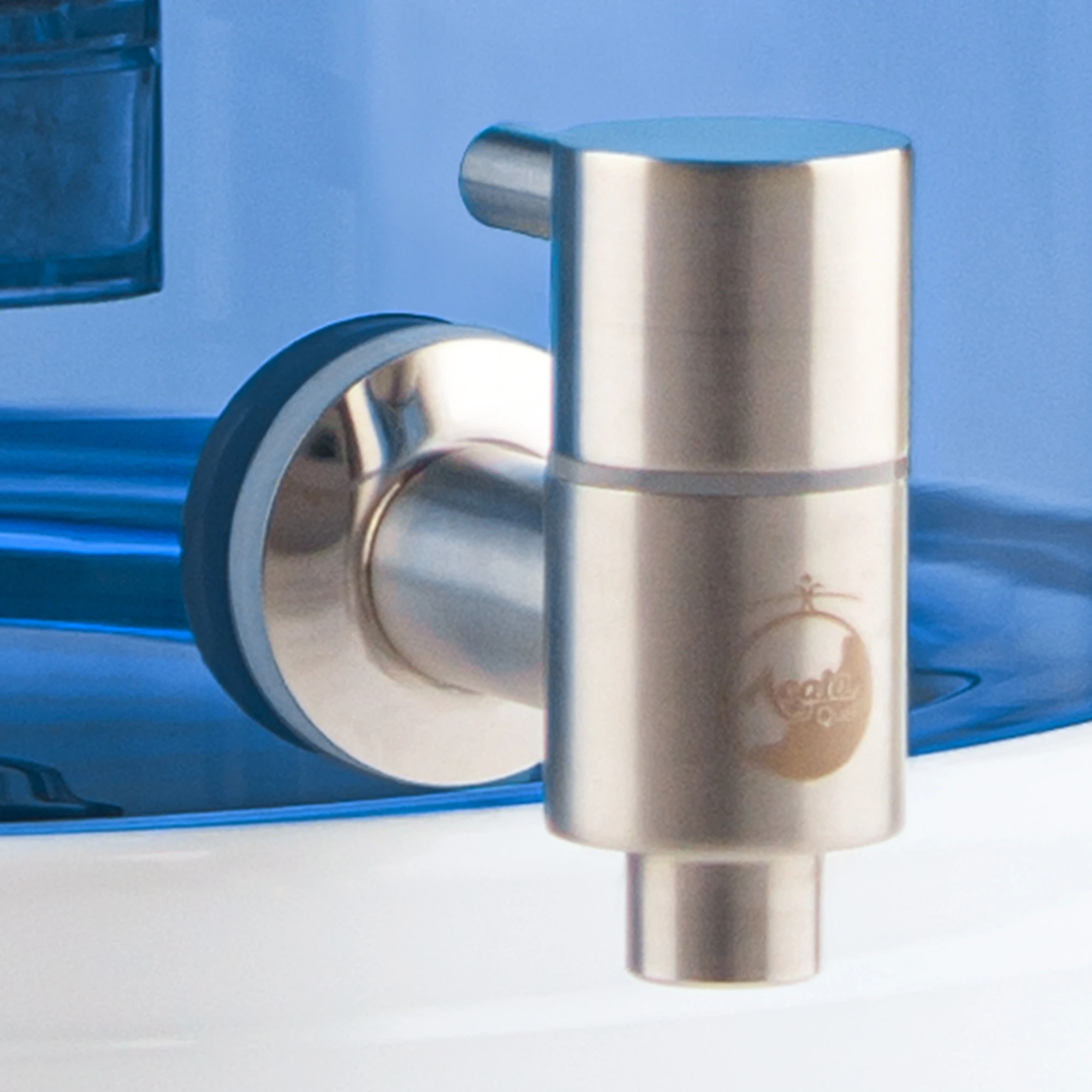 Zu sehen ist der Edelstahl Wasserhahn Makino für Acala Stand Wasserfilter an einem Glastank in blau montiert in Großaufnahme. Der Hahn ist silber und man sieht das AcalaQuell Logo darauf. 