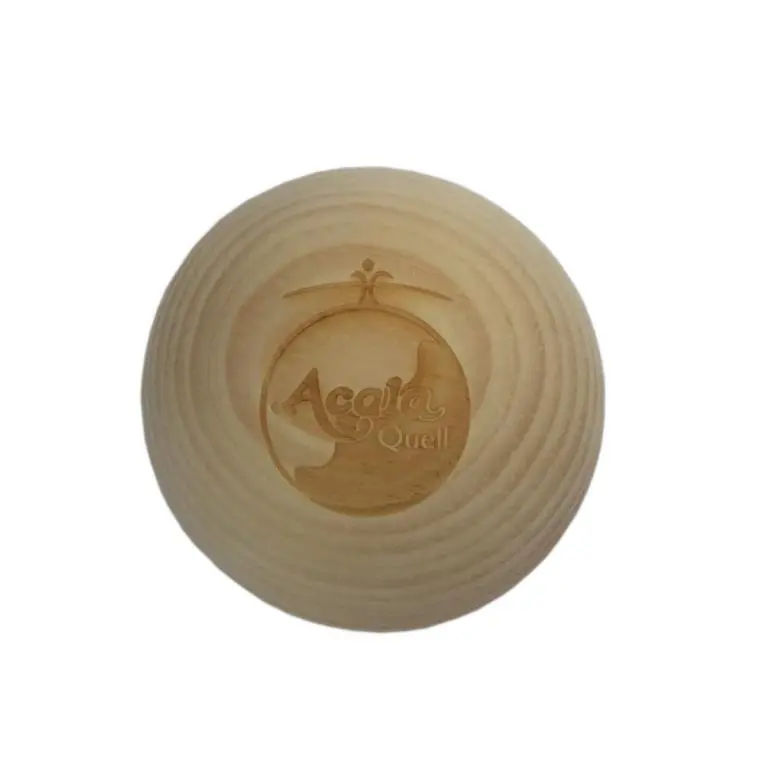 Zu sehen ist eine helle Holzkugel in Großaufnahme vor weißem Hintergrund. Auf der Kugel sieht man das Acala Logo. Das Bild zeigt die Zirbenholzkugel von Acala.
