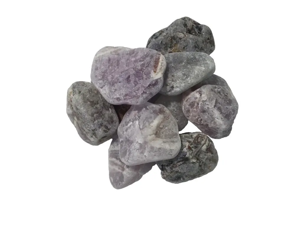 Zu sehen ist ein Haufen lila farbener Steine vor weißem Hintergrund. Das Bild zeigt die Amethyst Wassersteine von Acala. 