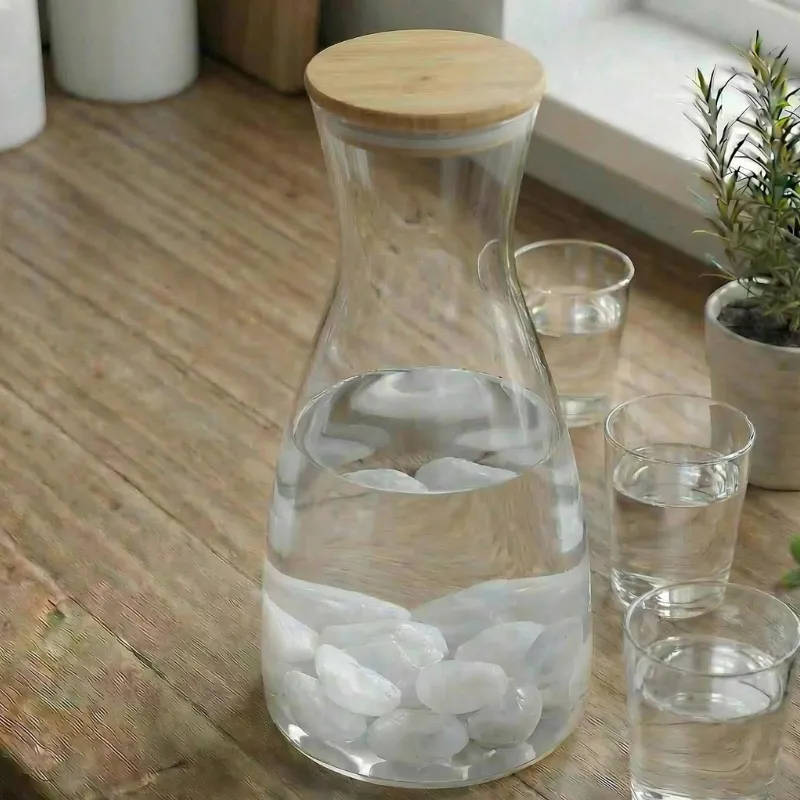 Eine Karaffe steht In der Küche darin ist Wasser mit Bergkristallen daneben stehen 3 Gläser mit Wasser
